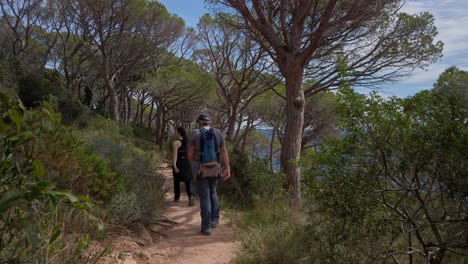 Los-Turistas-Caminan-Por-El-Sendero-Costero-A-Lo-Largo-De-Los-Acantilados-Paisaje-Soleado-Mediterráneo-Entorno-Verde-En-Sant-Feliu-De-Guixols,-Fondo-Del-Horizonte