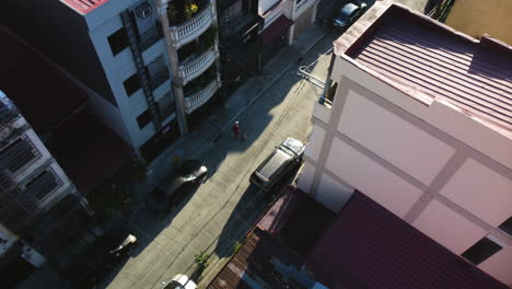 Drone-tracking-people-in-the-suburbs-of-Makati-city,-sunny-day-in-Manila,-Philippines
