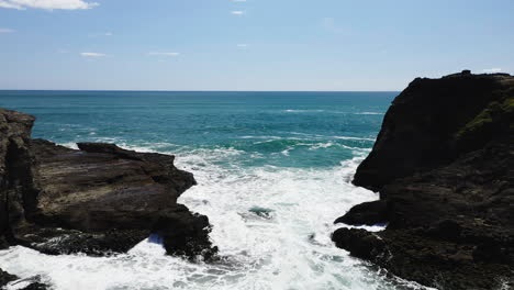 Reverse-reveal-of-people-in-a-sandy-cove-near-Piha-Beach-protected-by-volcanic-rock