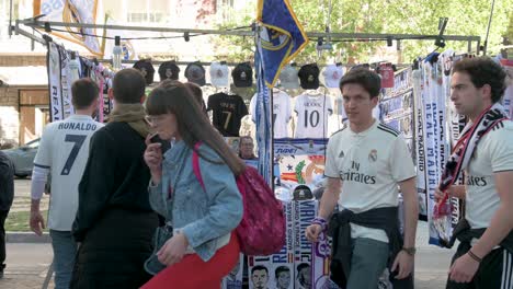 A-street-stall-selling-Real-Madrid-merchandise-such-as-scarves-and-jerseys-as-fans-walk-past-the-frame-before-attending-the-Champions-League-football-match-against-Manchester-City-football-team