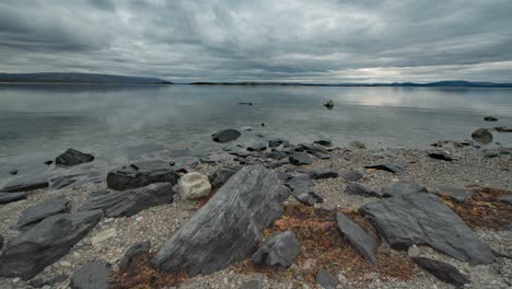 As-the-tide-slowly-rises,-stormy-clouds-move-fast-and-reflect-on-the-fjord's-mirror-like-surface,-captured-in-a-timelapse-video