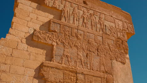 Chinese-woman-tourist-posing-for-a-photo-in-front-of-Egyptian-hieroglyphs-carved-red-wall-in-Ancient-Egypt,-Egyptian-language-in-oasis-North-Africa-desert