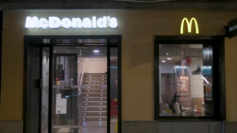 Nachts-Isst-Ein-Mädchen-In-Einem-McDonald&#39;s,-Einer-Amerikanischen-Fast-Food-Kette,-Während-Ein-Fußgänger-Vorbeigeht