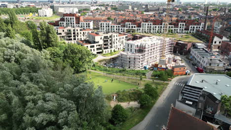 Lateral-Right-Aerial-View-of-Neighborhood-in-Ghent-Surrounded-by-Tall-Buildings-and-people-Playing-Football