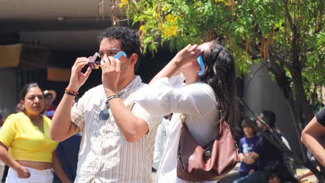 Latin-couple-observing-the-solar-eclipse-with-cardboard-sunglasses,-Mexico-April-8,-2024