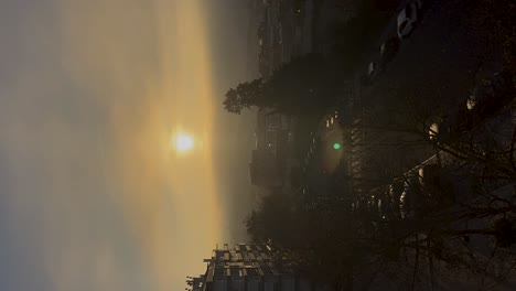 Misty-Sunrise-Over-Cascais-City-Buildings-and-Cars,-Soft-Morning-Light-and-Moving-Clouds,-vertical-timelapse