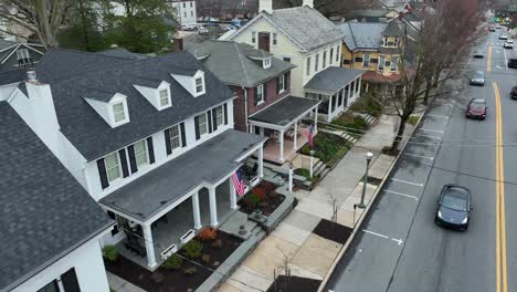 Establishing-drone-shot-of-american-house-and-porch-with-waving-american-flags-on-busy-street