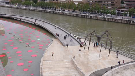 People-and-Spider-Sculpture-in-Front-of-Guggenheim-Art-Museum-in-Bilbao,-Spain