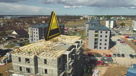 Roof-construction-on-an-apartment-with-a-graphic-hazard-sign-above-it---aerial