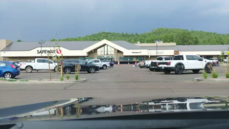 People-busy-near-shopping-mall-with-lightning-strike-above,-POV-from-inside-vehicle