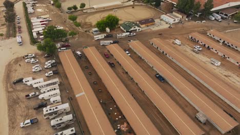 Toma-Aérea-De-Patios-De-Librea-En-El-Centro-Ecuestre-De-Burbank-La,-Drones-Sobre-Establos-Y-Caballos-En-El-Patio-De-Entrenamiento-Con-Remolques-Y-Camiones-Estacionados