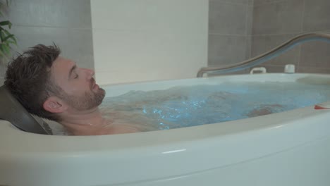 Slow-revealing-shot-of-an-attractive-man-relaxing-in-a-bubble-spa-tub