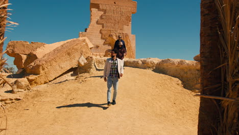 Tourist-visiting-ancient-Egyptian-remains-of-hieroglyphs-carved-wall-in-Siwa-oasis-north-African-desert-of-Egypt