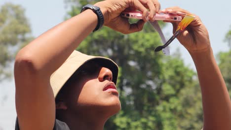 Latin-teenage-man-taking-a-photo-of-the-solar-eclipse-from-his-smartphone,-Mexico-April-8,-2024