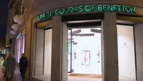 Käufer-Gehen-Nachts-Am-Geschäft-Der-Italienischen-Modemarke-United-Colors-Of-Benetton-Vorbei