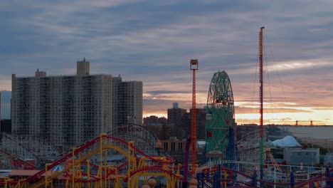 An-aerial-view-of-Coney-Island-amusement-park-in-Brooklyn,-NY-during-a-cloudy-but-colorful-sunrise