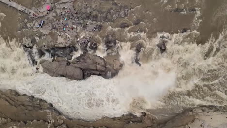 Turbulent-Flood-River-Fast-Flowing,-muddy-water-waving-after-big-rainstorms-and-floods-In-Rock-Mountain-Nature