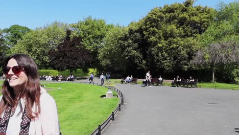 Charismatic-woman-smiles-as-she-walks-and-approaches-the-camera-at-Saint-Stephen's-Green-Park,-Dublin