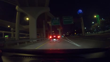 Series-number-three-hyperlapse-showing-car-driving-through-downtown-Dallas-Texas-at-night-with-interstate-driving,-sudden-traffic-merge,-and-with-large-city-towers-lit-up-in-the-background