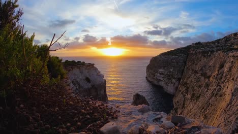 Golden-sunset-captured-in-a-time-lapse,-descending-over-serene-rocky-cliffs-by-the-sea