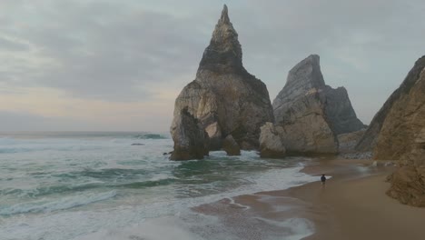 A-guy-running-on-a-rocky-sand-beach-surrounded-by-cliffs