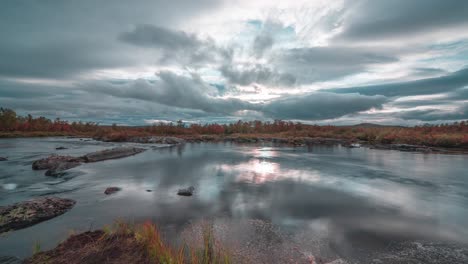 Stormy-clouds-move-fast-in-the-sunset-skies-and-are-reflected-in-the-glassy-river-surface