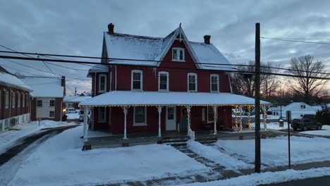 Aerial-approaching-shot-of-snowy-Single-Family-House-decorated-with-christmas-lights-in-winter-snow