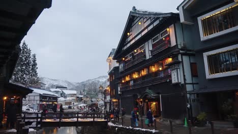 Slow-motion-establishing-shot-pan-in-early-evening,-peaceful-Japanese-town-in-the-snow
