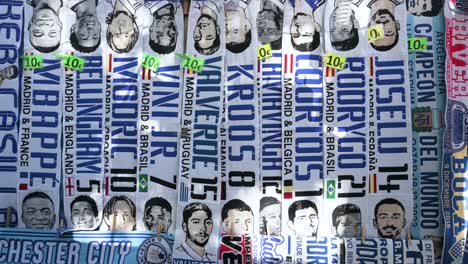 Real-Madrid-theme-scarves,-including-Kylian-Mbappé-design,-are-seen-for-sale-near-the-Santiago-Bernabeu-stadium-during-the-Champions-League-football-match-against-Manchester-City