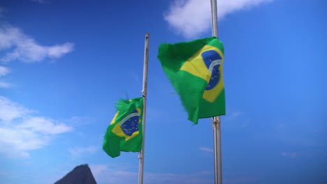 Showcasing-the-pair-of-Brazilian-flags-fluttering-in-Copa-Cabana,-Rio-de-Janeiro,-Brazil,-set-against-the-captivating-backdrop-of-azure-skies