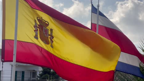 Spanish-and-Costa-Rican-flags-waving-against-cloudy-sky