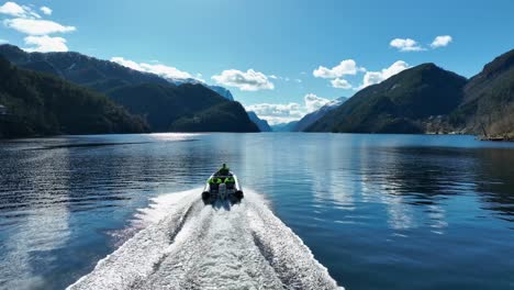 Turistas-En-Zodiac-Navegando-A-Alta-Velocidad-Hacia-Veafjord-En-Primavera,-Seguimiento-Aéreo