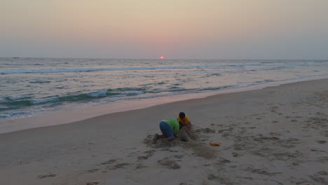 Brothers-playing-in-beach,-children's-playing-with-sand-at-sunset