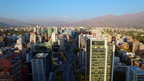 Drohnenüberflug-über-Die-Apoquindo-Avenue-Im-Stadtteil-Las-Condes,-Skyline-Der-Wolkenkratzer-Mit-Den-Anden-In-Der-Ferne,-Santiago