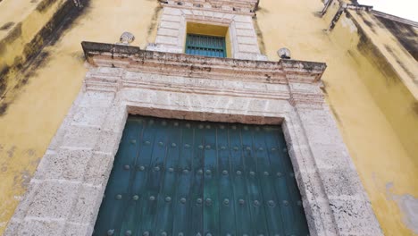 Massive-green-door-and-golden-painted-facade-of-Holy-Trinity-church,-Cartagena