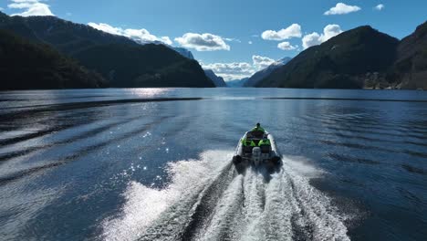 Tourists-on-fjord-safari-adventure-onboard-RIB-speedboat,-Aerial-follow-behind-60fps