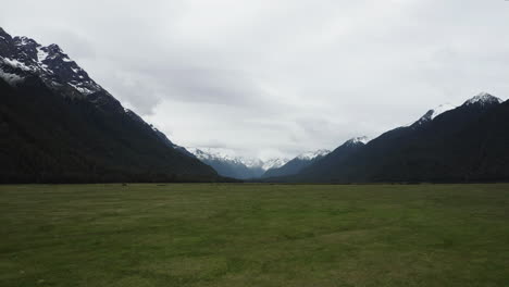 Reverse-reveal-of-Eglinton-Valley-grassland-plains-flanked-by-towering-mountains
