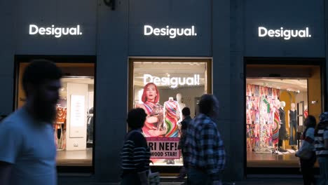 Compradores-Y-Peatones-Pasan-Por-La-Tienda-De-Ropa-Española-Desigual-Durante-La-Noche