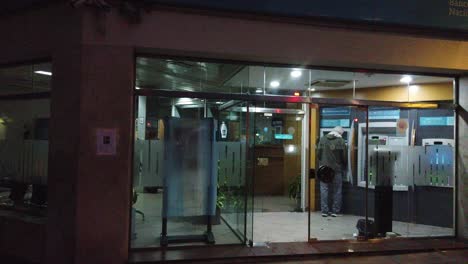 National-Bank-of-argentina-entrance-people-take-money-from-ATM-banco-nacion-public-government-commercial-store-at-night,-people-walking-by