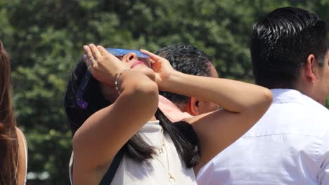Latin-woman-observing-the-solar-eclipse-with-cardboard-sunglasses,-Mexico-April-8,-2024