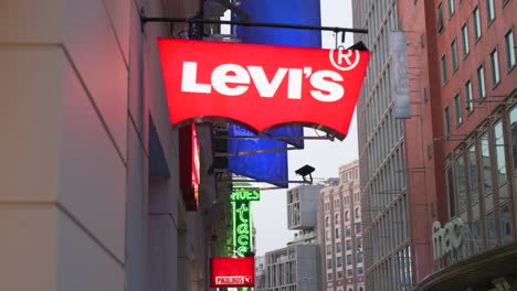 La-Marca-De-La-Compañía-De-Ropa-Americana,-La-Tienda-Levi&#39;s-Y-El-Logotipo-En-Una-Calle-Comercial-Por-La-Noche