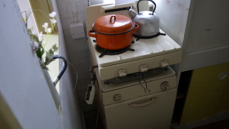 Vintage-kitchen-stove-with-an-orange-pot-and-kettle,-showcasing-retro-cooking-appliances