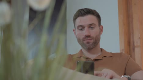 Slow-motion-revealing-shot-of-an-attractive-man-using-his-smartphone
