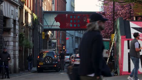 Lebendige-Straßenszene-Im-Nördlichen-Viertel-Von-Manchester,-Rote-Kunstwerkbrücke,-Fußgänger