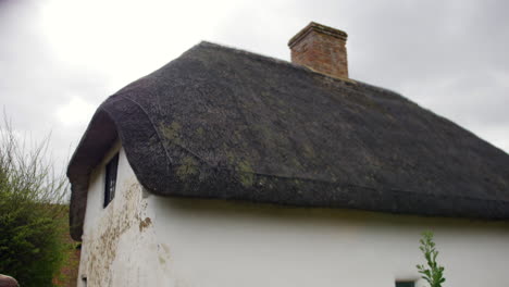 Thatched-cottage-roof-with-distinctive-curved-design-and-a-mossy-texture,-symbolizing-traditional-architecture
