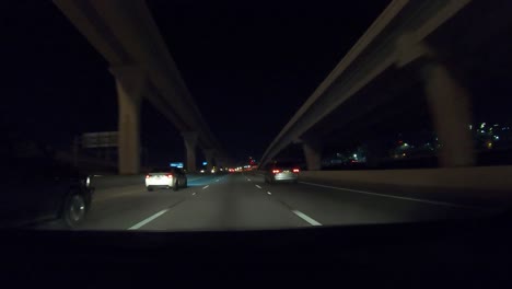 Hyperlapse-Der-Serie-Nummer-Acht-Zeigt-Ein-Auto,-Das-Nachts-Aus-Der-Innenstadt-Von-Dallas,-Texas,-Wegfährt,-Mit-Lichtern-Der-Stadt,-Einem-Großen-Verkehrsknotenpunkt-Und-Allgemeinem-Fahren-Auf-Der-Autobahn