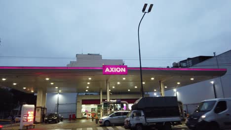 Estación-De-Gasoil-Rosa-Axion-Estableciendo-Un-Disparo-En-La-Avenida-De-La-Ciudad-De-Buenos-Aires-Tráfico-Cielo-Del-Atardecer