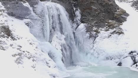 Helgufoss-waterfall-in-early-Spring,-with-ice-and-falling-snow