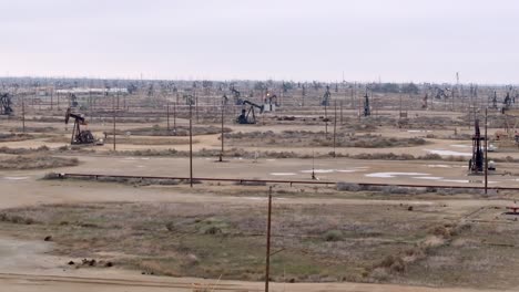 Oil-well-field-with-derrick-pumps-in-the-desert---aerial-flyover