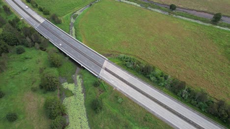 Luftaufnahme-Des-Pacific-Motorway-Mit-Fahrzeugen,-Die-Bei-Tageslicht-Durch-Felder-Fahren